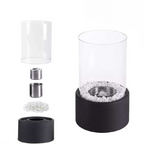 Oil lamp with open flame in clear glass cylinder on metal frame with decorative stones