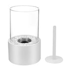 Oil lamp with open flame in clear glass cylinder on metal frame with decorative stones