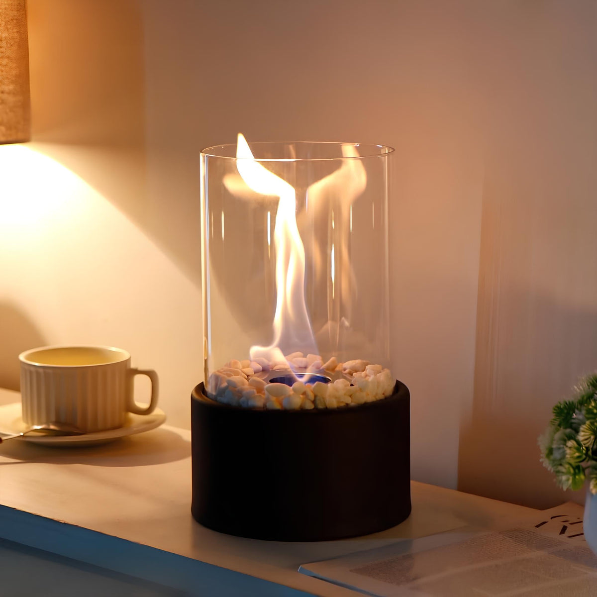 Oil lamp with open flame in clear glass cylinder on metal frame with decorative stones
