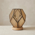 Geometric glass table lamp amber with wood base and exposed metal profiles, warm diffused light