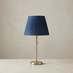 Table lamp with blue pleated fabric shade and brass metal base, soft ambient light
