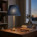 Table lamp with blue pleated fabric shade and brass metal base, soft ambient light