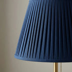 Table lamp with blue pleated fabric shade and brass metal base, soft ambient light
