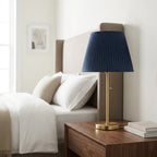 Table lamp with blue pleated fabric shade and brass metal base, soft ambient light