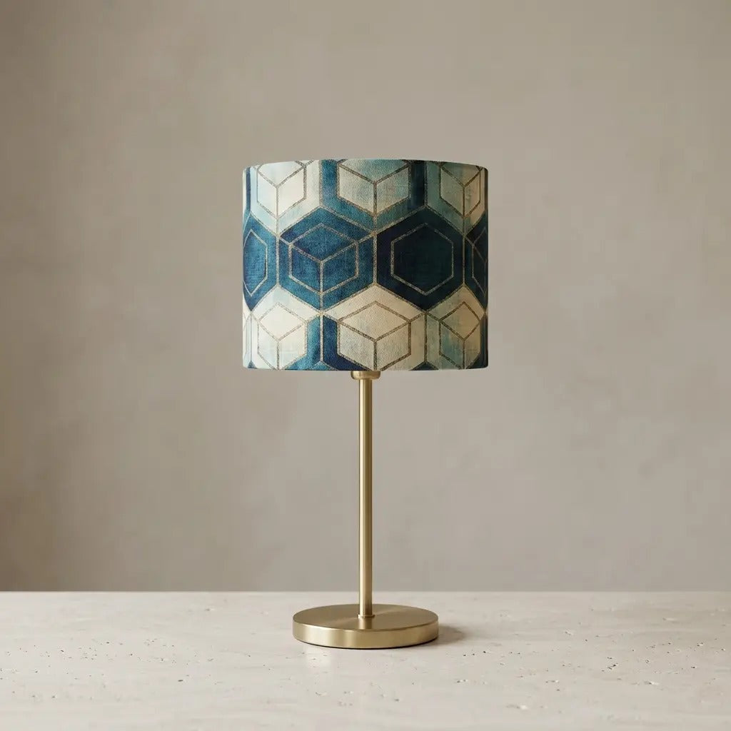 Table lamp with geometric patterned cylindrical shade and brass metal base, warm diffused light