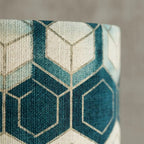 Table lamp with geometric patterned cylindrical shade and brass metal base, warm diffused light