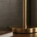 Table lamp with geometric patterned cylindrical shade and brass metal base, warm diffused light
