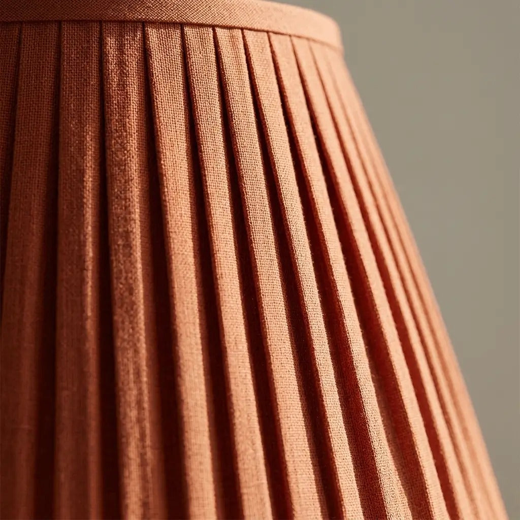 Table lamp with terracotta pleated fabric shade and slim pale matt metal base