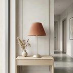 Table lamp with terracotta pleated fabric shade and slim pale matt metal base